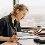 A woman sitting at a table with papers and a calculator.