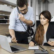 A man and woman sitting at a table with laptops.