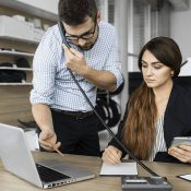 A man and woman working on laptops at a table.