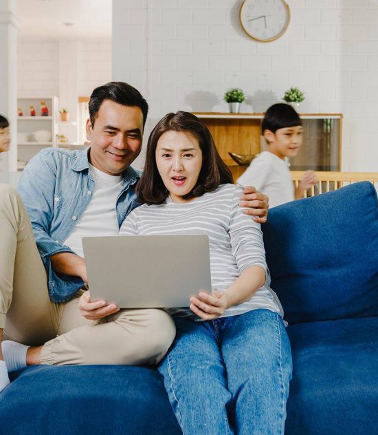 A man and woman sitting on the couch with a laptop.